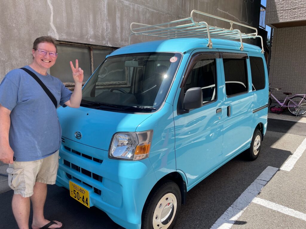 Man standing by blue Japanese van