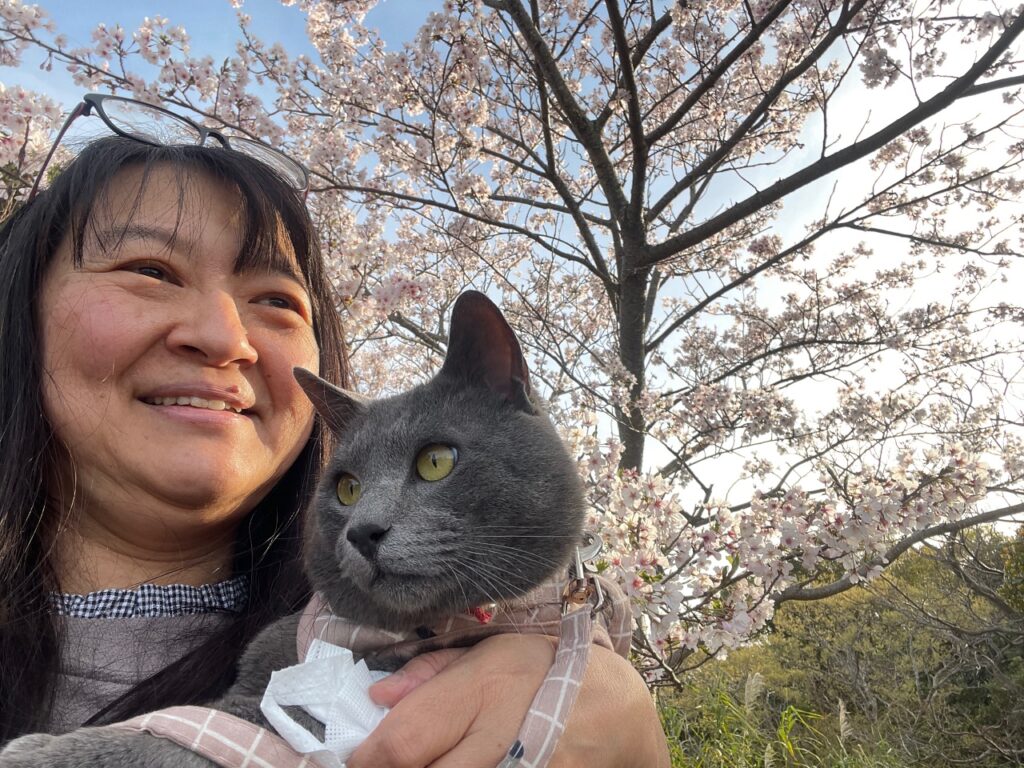 Woman holding cat by cherry trees in Wakayama Japan